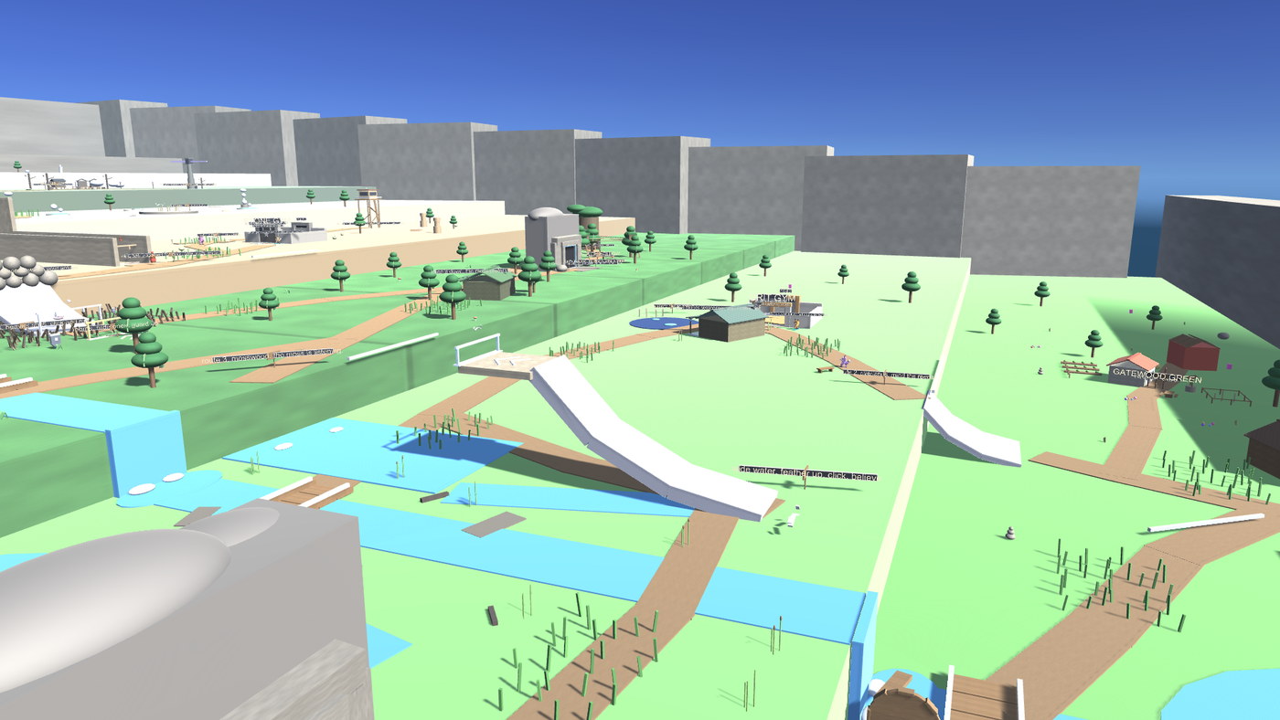 The lower park seen from above: green terraces stepping down past a blue creek that widens into ponds, dirt trails running between them, a tall white curved ramp beside one path, scattered low trees, a ranger hut and a signed village, with grey cliff walls closing the far side.